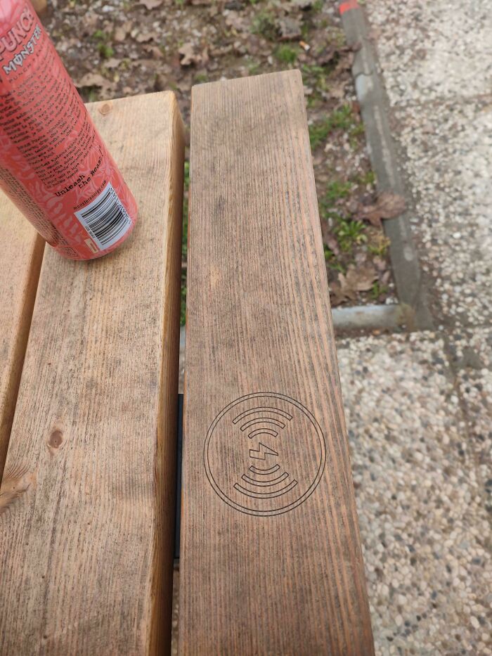 A wooden bench with wireless charging symbol, showcasing a Cities-Genius-Solutions innovation.