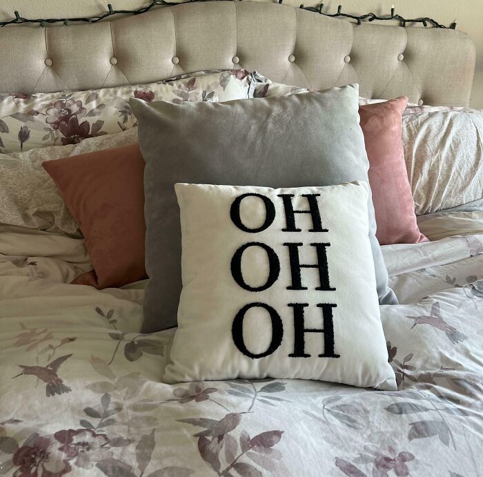 Valentine's gift idea: quirky pillows with "OH OH OH" text on a floral-patterned bed.
