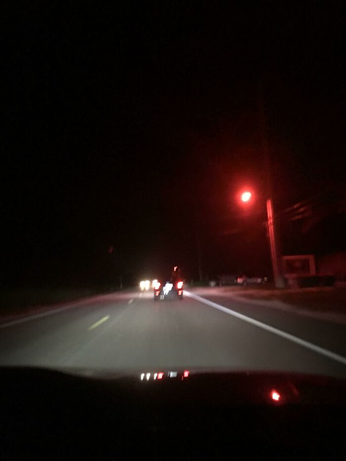 A car on a dark road with a distant red light, showcasing urban challenges and solutions in Cities-Genius-Solutions.