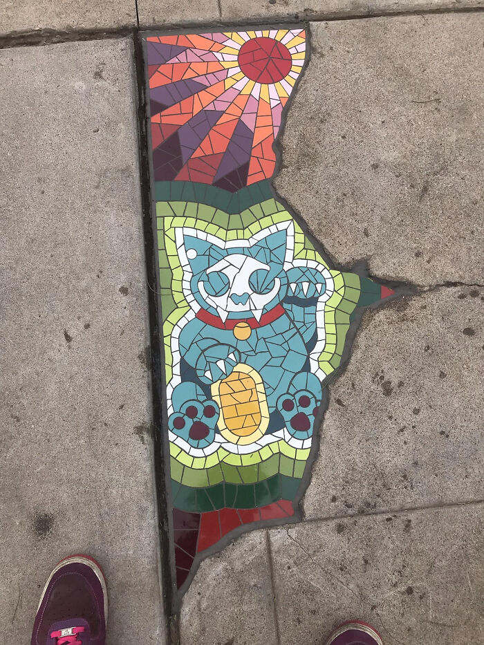 Colorful cat mosaic embedded in sidewalk, illustrating Cities-Genius-Solutions in urban art.