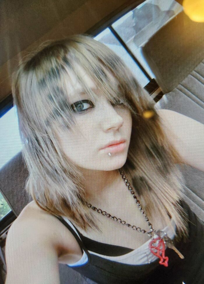 Teen with emo hairstyle and lip piercing taking a selfie, reflecting on their regrettable past style and cringe-worthy moments.