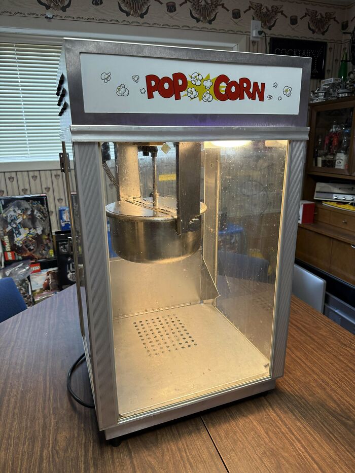Vintage popcorn machine found while thrifting sits on a wooden table.