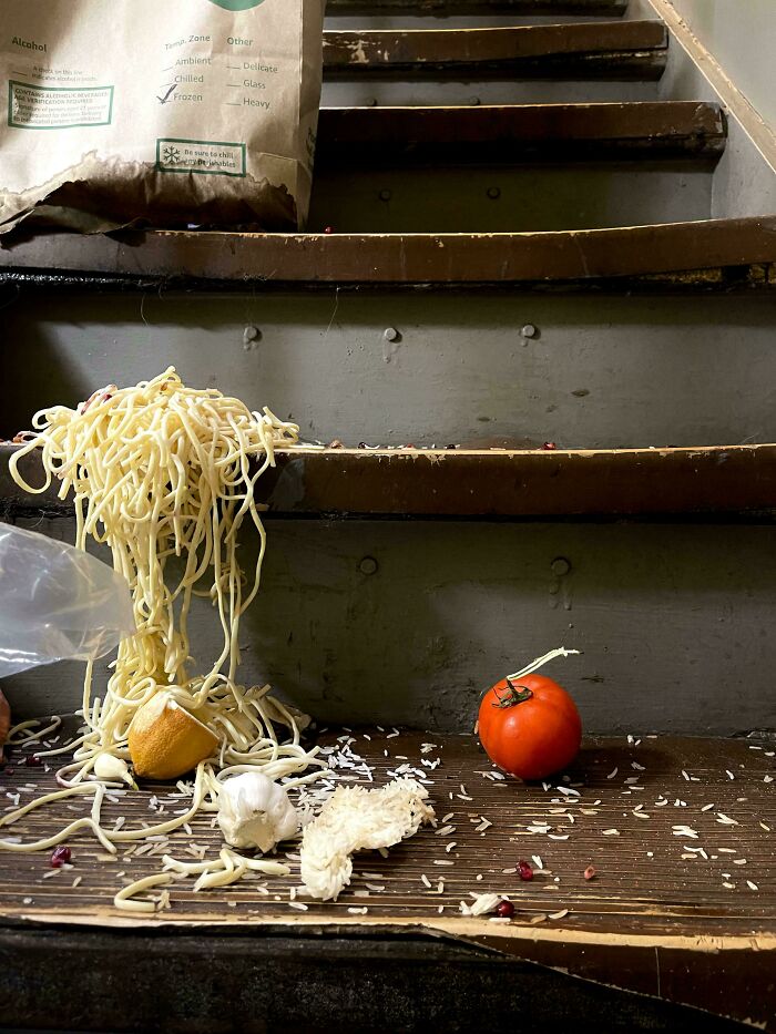 Spilled noodles and produce on wooden steps, resembling an accidental Renaissance painting.