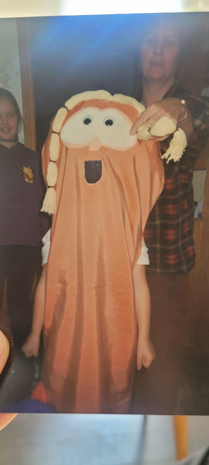 Child in homemade goofy costume with a large face and braided yarn hair from regrettable past photos collection.