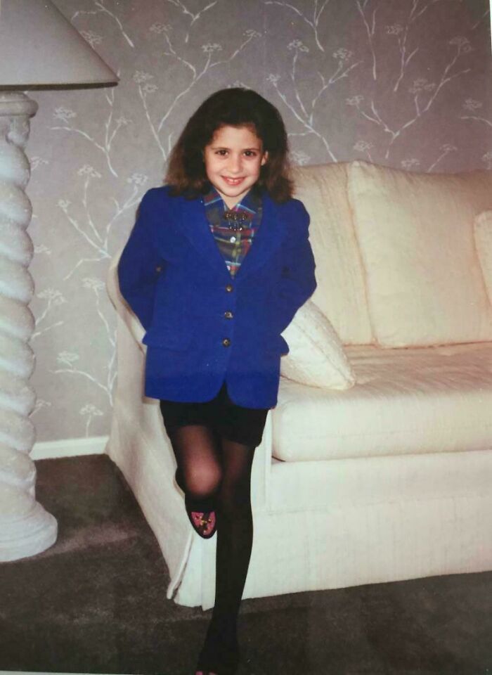 Young girl in vintage outfit posing with one leg up by a classic couch, part of regrettable past cringe pics collection.