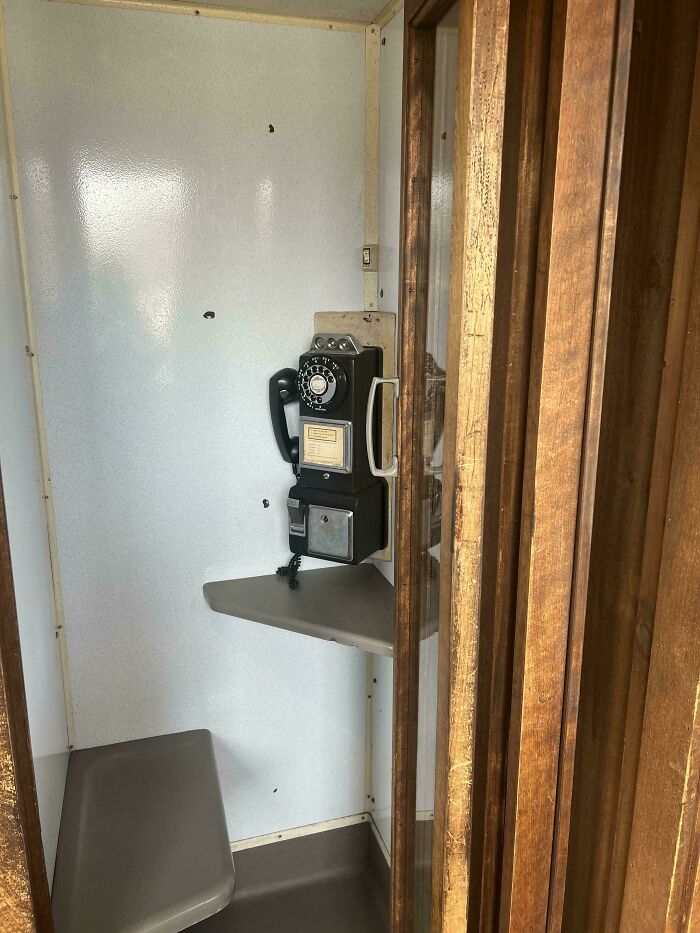 Retro phone booth with a rotary dial phone, wooden details, evoking nostalgia.