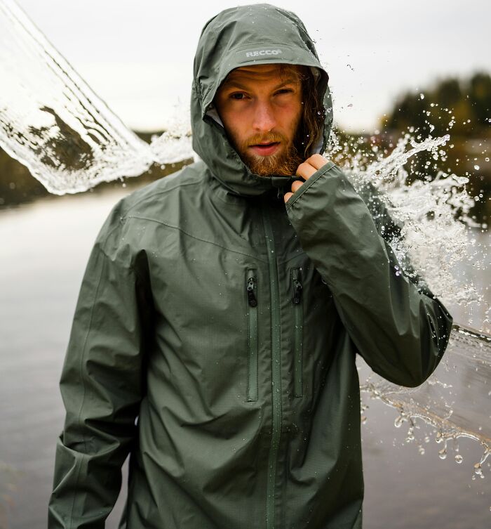 Person in a green rain jacket being splashed with water, showcasing 2025-Trends in outdoor fashion.