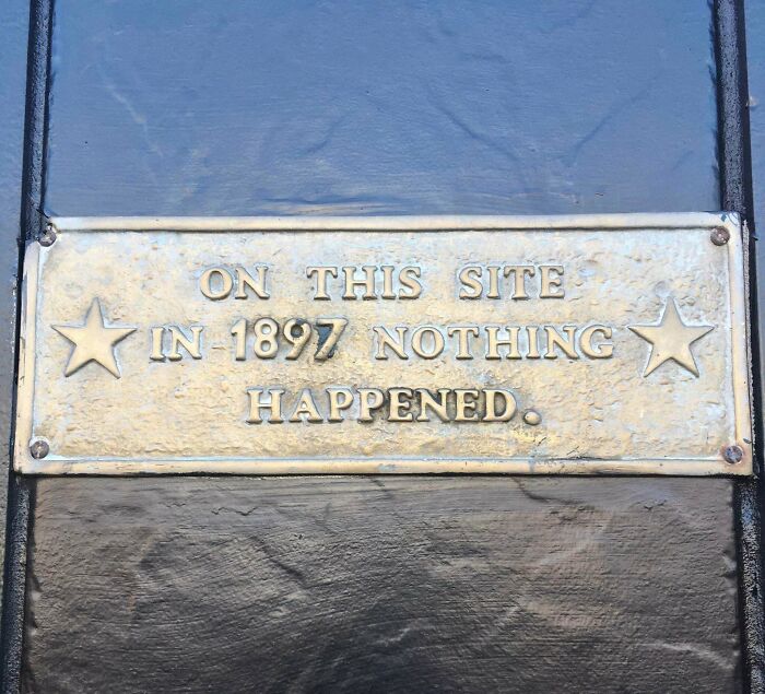 Funny sign with text: "On this site in 1897 nothing happened," displayed on a metal plaque.