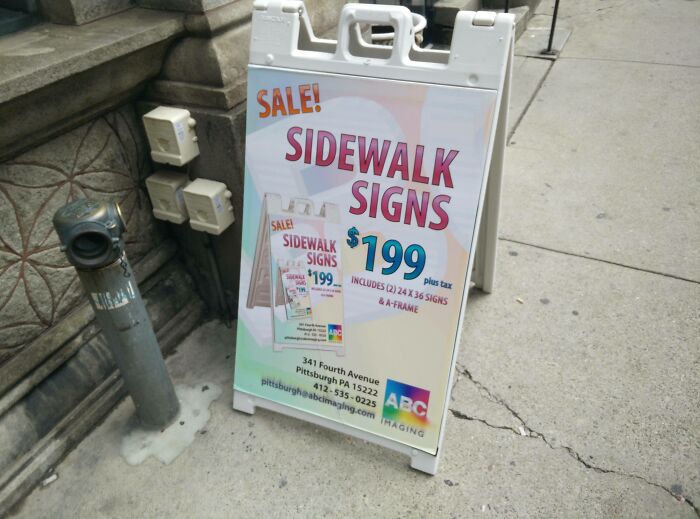 Sidewalk signs advertisement for $199 on a city street, featuring colorful design and sale promotion.