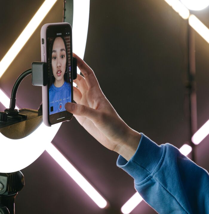 Person capturing a selfie on a smartphone with neon lights, showcasing 2025-Trends in digital content creation.