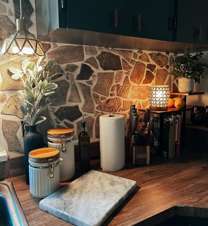 Cozy kitchen scene with rustic stone backsplash and soft lighting, showcasing 2025 interior trends.
