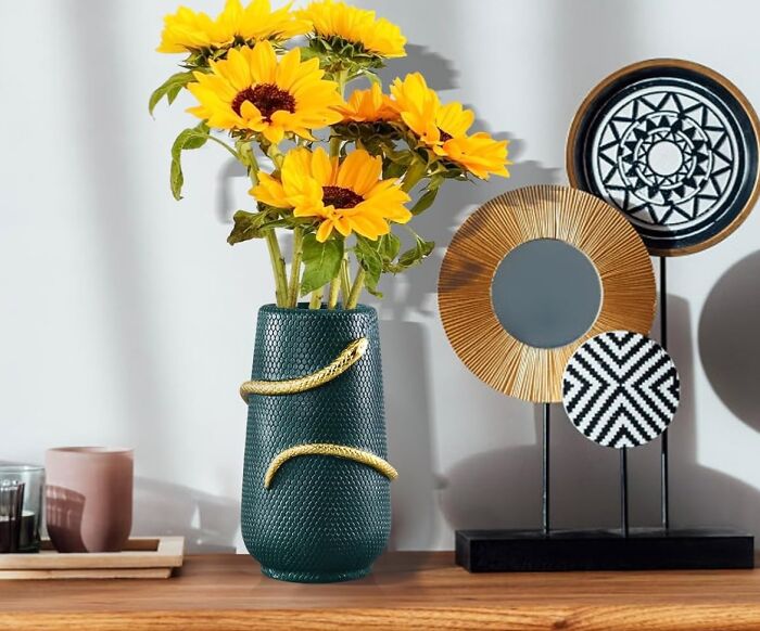 Sunflowers in a textured vase on a table with decorative mirrors, showcasing 2025 interior trends.