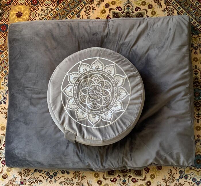 Gray cushion with intricate mandala design on a patterned rug, highlighting 2025 interior trends.