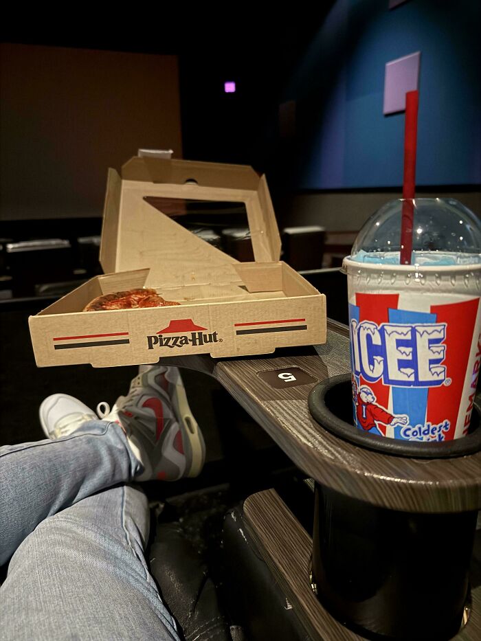 Pizza Hut box and ICEE drink in a '90s-themed theater setting.