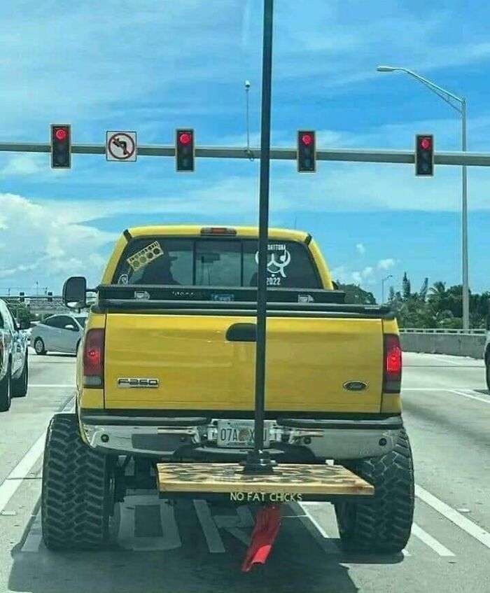 Yellow truck with lifted suspension and rear platform at a Florida traffic light, illustrating wild road moments.