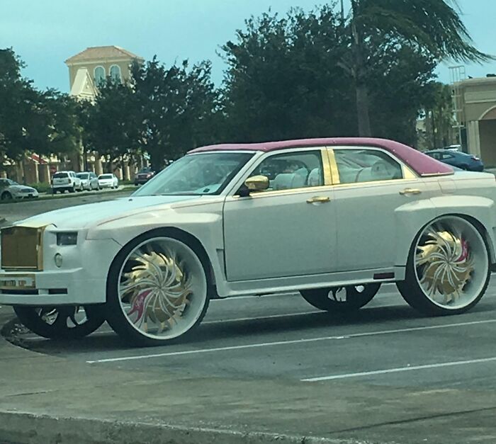 Customized white luxury car with pink roof and ornate wheels, parked in a Florida lot, capturing Florida wild moments.