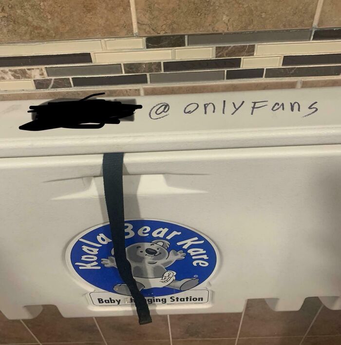 Graffiti on a baby changing station with "onlyFans" and text blurred out, depicting a humorous Florida wild moment.