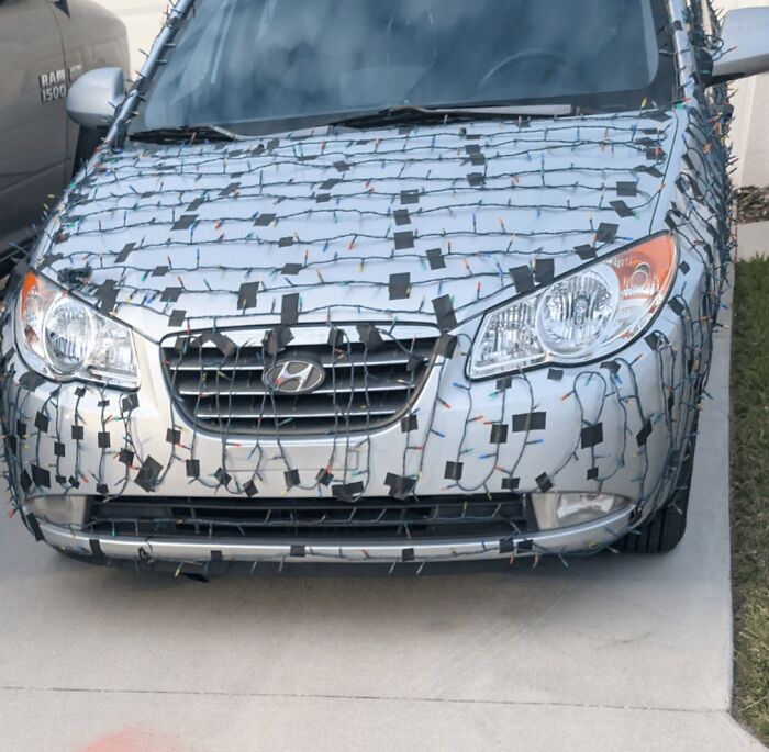 Car covered in festive holiday lights in a parking lot, showcasing Florida wild moments.