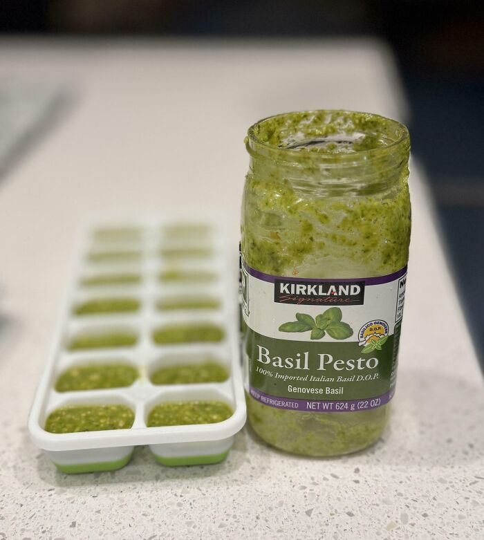 Jar of basil pesto with filled ice cube tray for grocery shopping hacks.