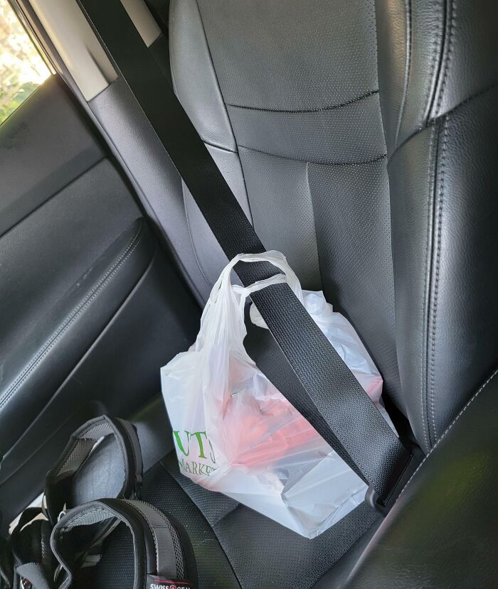 Plastic grocery bag secured with a seatbelt on a car seat, showcasing grocery-shopping-hacks.