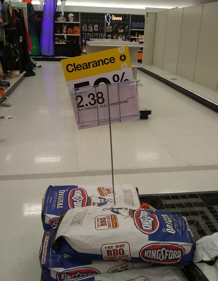 Clearance sign in a grocery store showing a 50% discount on Kingsford charcoal bags, illustrating grocery-shopping hacks.
