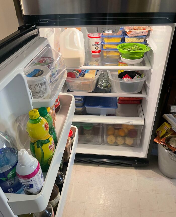 Open fridge organized with groceries, featuring items like milk, eggs, and produce, demonstrating grocery-shopping-hacks.