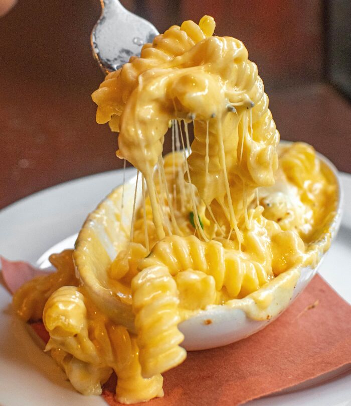 Cheesy pasta being lifted from a dish, showcasing eye-opening moments of gooey goodness.