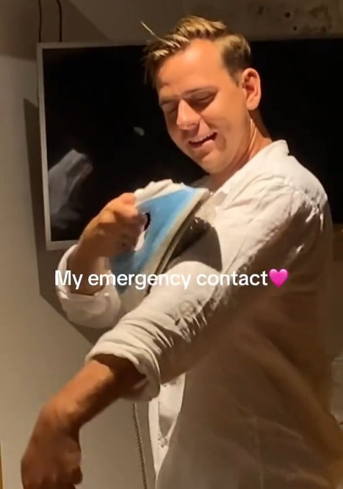 Man humorously ironing his sleeve, implying an emergency situation indoors.