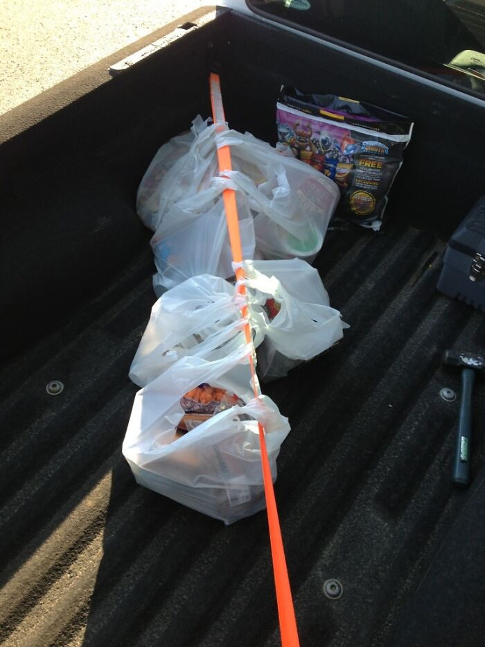 Plastic bags secured with a strap in a truck bed, showcasing grocery shopping hacks.