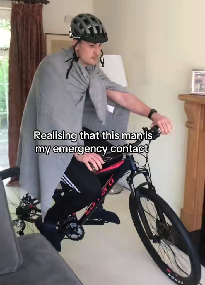 Man in a helmet and blanket on a bicycle indoors, humorously labeled as an emergency contact crisis.