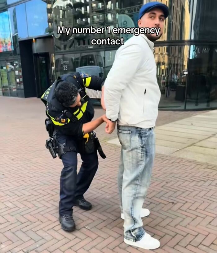 Police officer handling an emergency situation with a man in handcuffs on a city street.