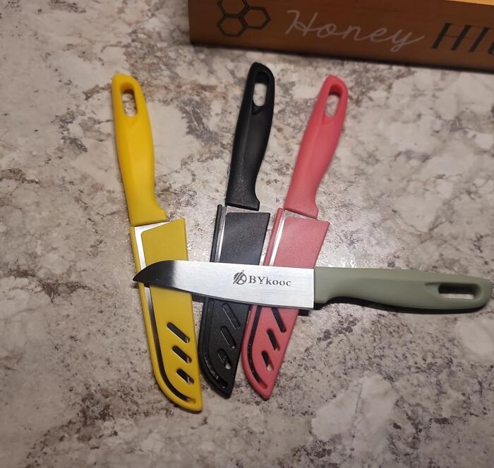 Colorful kitchen knives with sheaths displayed on a marble countertop, affordable items under five dollars.