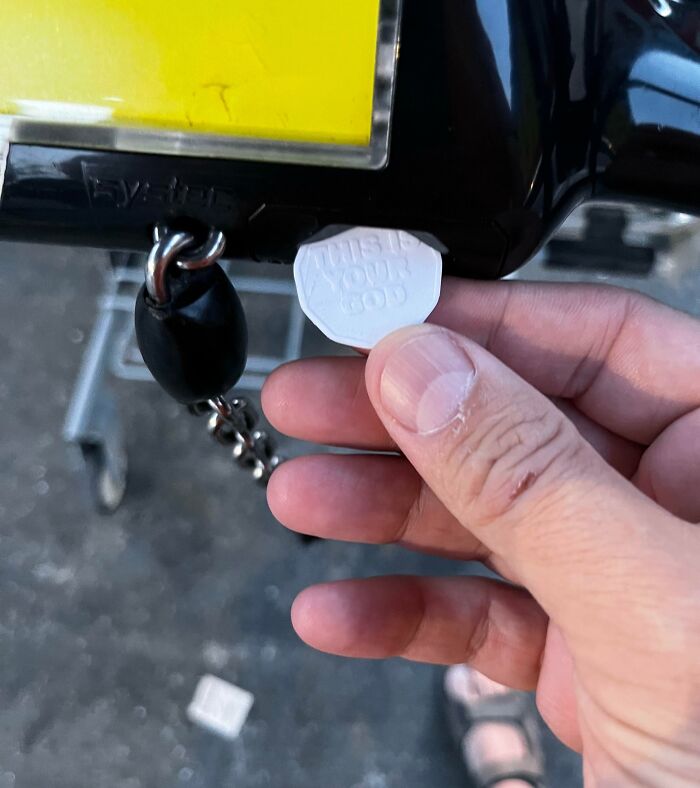 Hand demonstrating a grocery-shopping-hack by using a token to unlock a shopping cart.