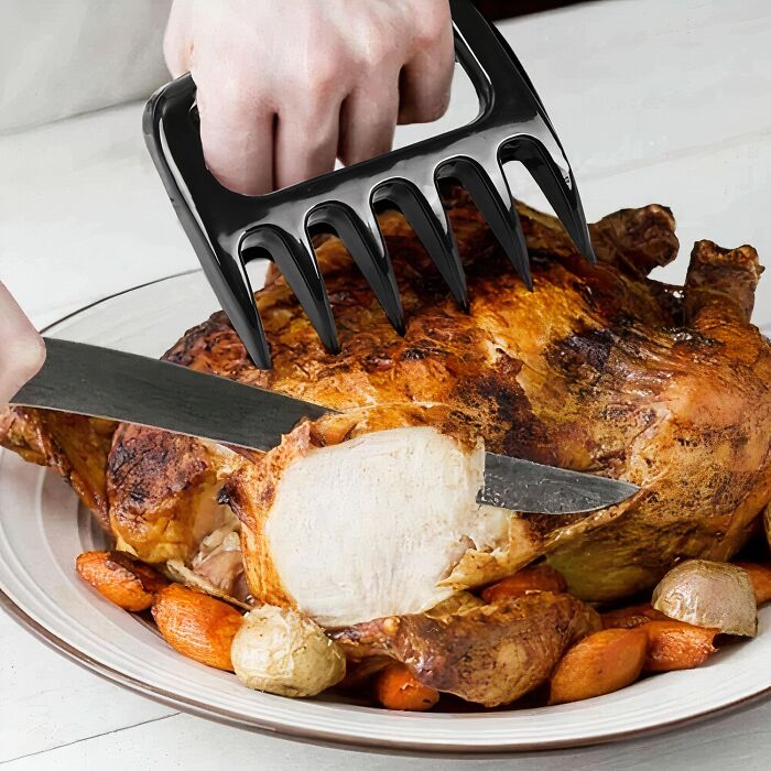 Hand using meat claws and knife to carve a roasted chicken with vegetables, highlighting affordable items under $5.