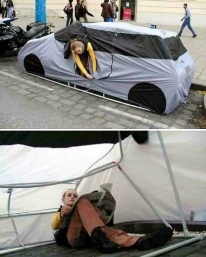 A person is inside a car-shaped tent on the sidewalk, highlighting issues of capitalism in America.