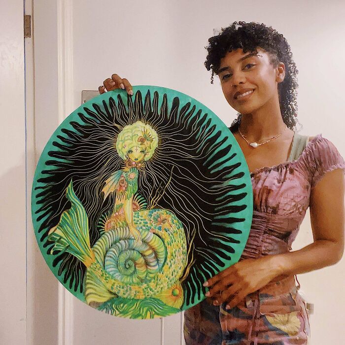 Person holding a circular DIY project featuring a vibrant mermaid design.