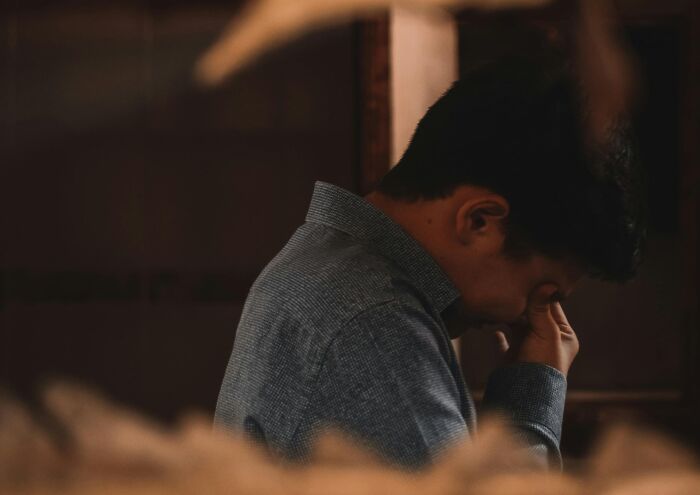 A person in a moment of realization, wearing a blue shirt, touching their face, symbolizing eye-opening moments.