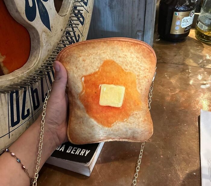 A hand holding a toast-shaped purse with butter design, showcasing one of the weird things that actually exist.