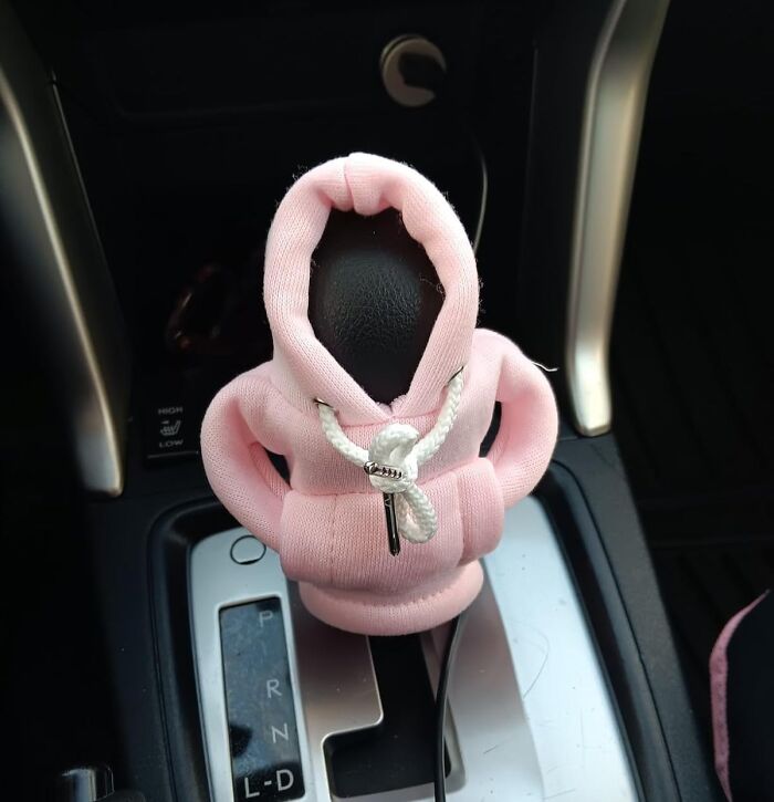 Weird pink hoodie-shaped gear shift cover in a car interior.