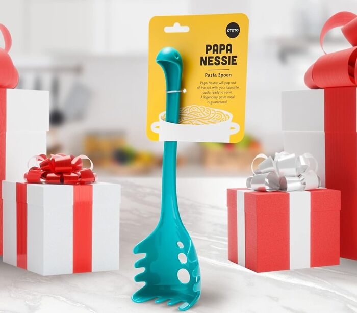 Unique pasta spoon shaped like Nessie with gift boxes in the background.