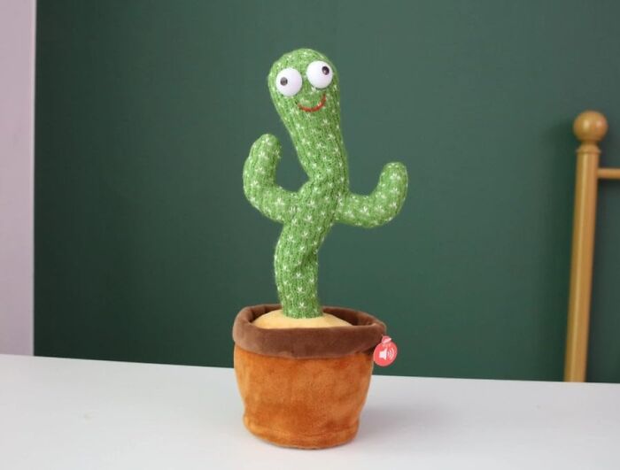 Cute plush cactus toy with googly eyes and a smile, standing in a brown pot against a green background. Weird things exist.