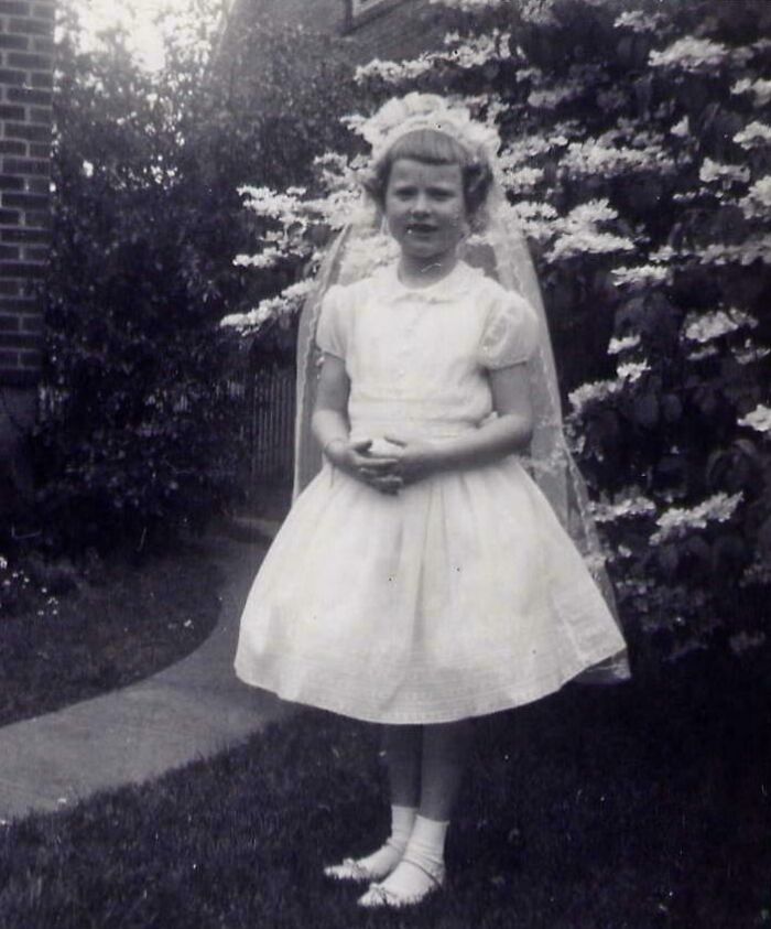 A young girl in a white dress and veil stands outdoors, associated with photographs with terrifying backstories.