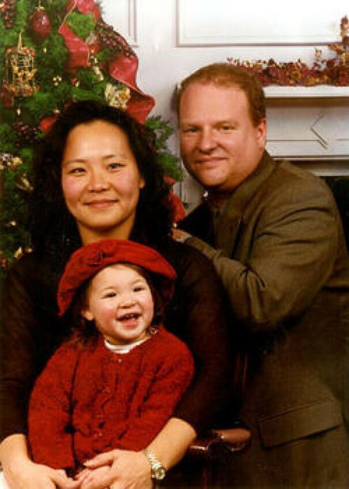 Family posing in front of a Christmas tree, smiling; haunting backstory linked to the photograph.