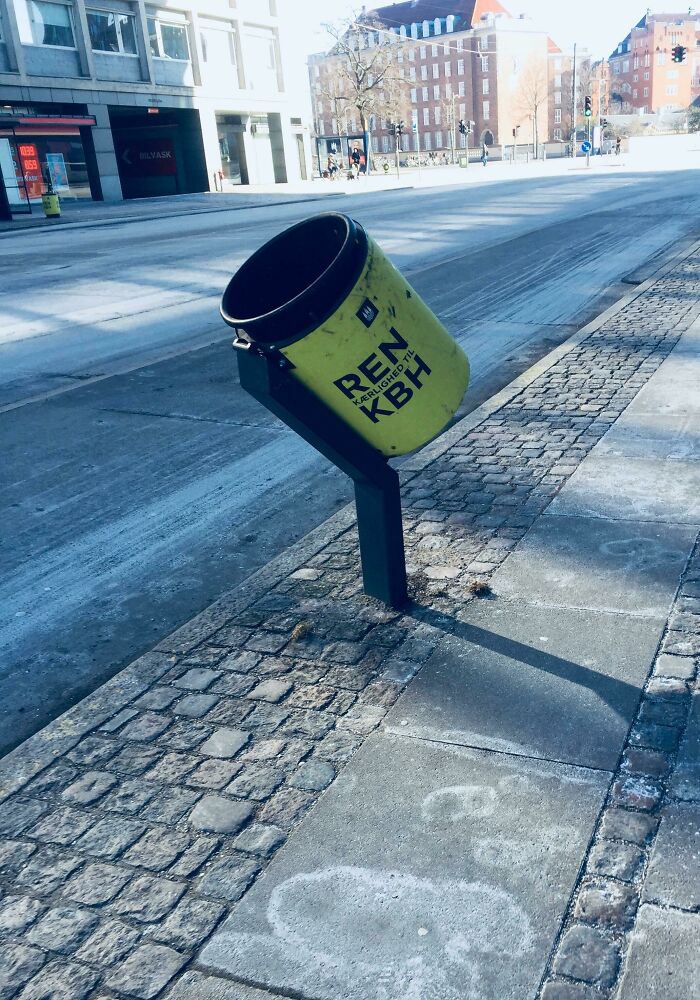 Tilted trash can on a city street, showcasing urban design solutions for cleaner cities.