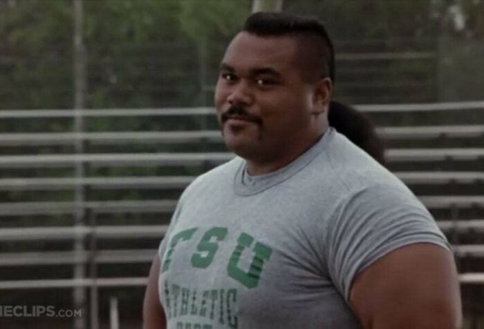 Man in a gray T-shirt at a sports field, evoking iconic '90s style and nostalgia.
