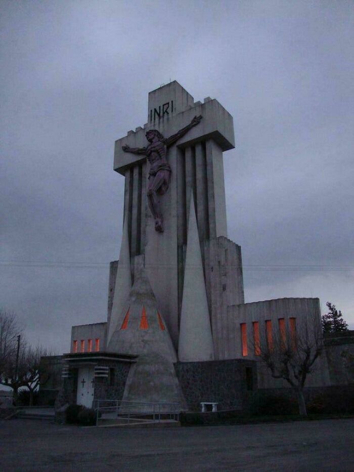 Tall concrete building with a dark statue and glowing windows, exuding an evil aura like a supervillain headquarters.