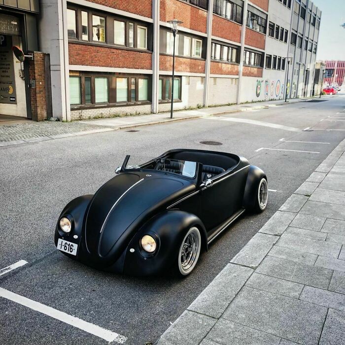 Matte black vintage car parked on a city street, showcasing classic design.