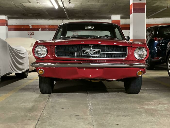 Vintage car parked in a dimly lit garage, showcasing its classic red front design.