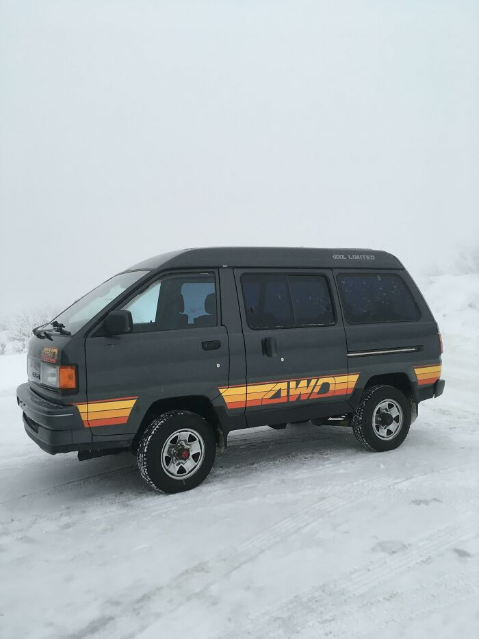 A vintage AWD van parked on a snowy landscape.