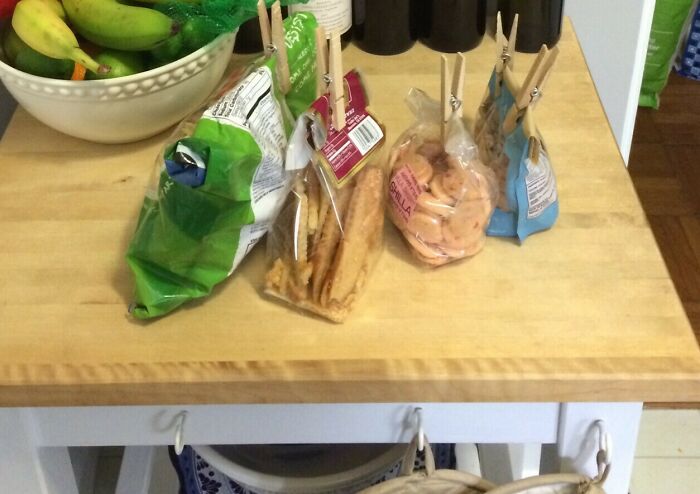 Grocery-shopping-hacks: Wine bottles, fresh fruits, and sealed snacks organized neatly on a wooden kitchen counter.